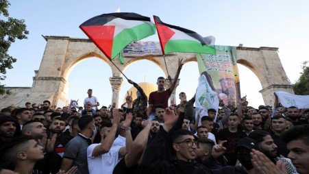 People wave Palestinian flags during Eid al-Fitr prayers at the compound that houses Al-Aqsa Mosque in Jerusalem's Old City.